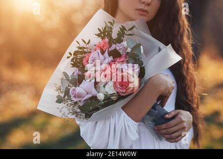 Jeune femme en robe blanche tenant un beau bouquet de roses Banque D'Images