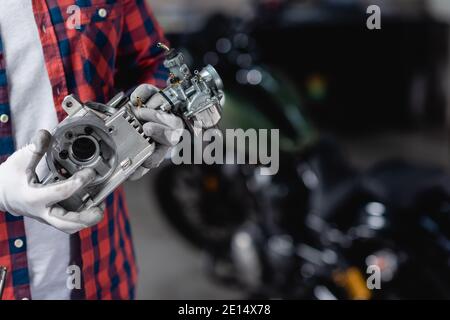 vue rognée du mécanicien dans des gants tenant une partie de la moto transmission Banque D'Images