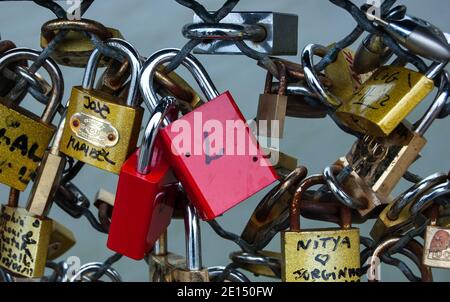 Deux cadenas rouges attachés parmi les autres serrures d'amour qui sont fixés à la clôture du pont à Paris. Gros plan. Banque D'Images