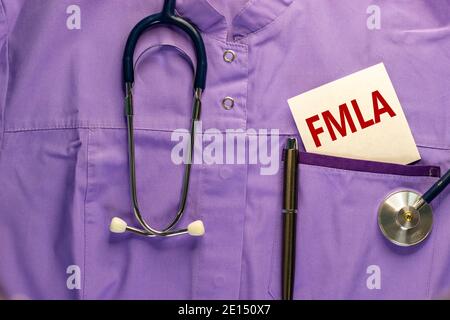 Symbole FMLA. Uniforme médical, carte blanche avec les mots « FMLA - Family Medical Leave Act », stylo métallique et stéthoscope. Médical et FMLA - médecine familiale Banque D'Images