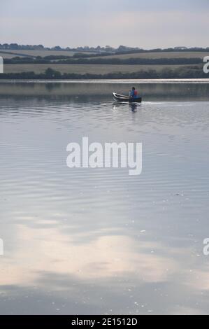 Une jeune dame pagayer un canot canadien dans une eau calme Un estuaire de Cornouailles Banque D'Images