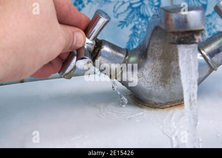 L'eau fuit d'un vieux robinet rouillé dans la salle de bains, la plomberie de la maison. Banque D'Images