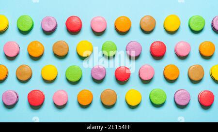 Vue de dessus avec macarons faits maison isolés sur un fond bleu. Macarons multicolores alignés symétriquement. Macarons sucrés cuits après le REC. français Banque D'Images