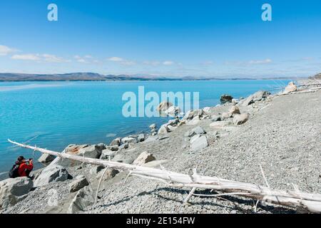 Femme en train de se brouiller prenant la photo sur le bord gris de lac de poney et bleu turquoise de l'eau de la neige d'alimentation pittoresque lac Pukaiki dans le sud de l'Ilsand Nouvelle-Zélande. Banque D'Images