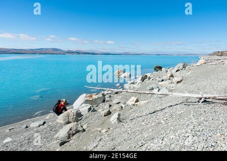 Femme en train de se brouiller prenant la photo sur le bord gris de lac de poney et bleu turquoise de l'eau de la neige d'alimentation pittoresque lac Pukaiki dans le sud de l'Ilsand Nouvelle-Zélande. Banque D'Images