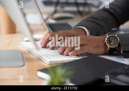 vue rognée du commerçant en tapant sur le clavier de la montre-bracelet premier plan flou Banque D'Images