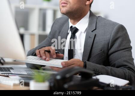 vue rognée de la saisie de commerçant sur le clavier dans le bureau, flou de premier plan Banque D'Images