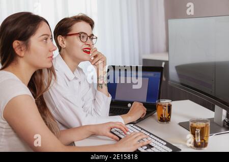 Deux jeunes employées de l'industrie INFORMATIQUE utilisent l'ordinateur ensemble. Femmes développeurs travaillant sur le projet logiciel Banque D'Images