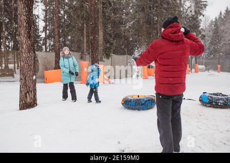 Minsk, Bélarus - 03 décembre 2020 : une famille amicale jouant des boules de neige dans une forêt enneigée - papa et enfant de maman s'amusent pendant les vacances de noël Banque D'Images