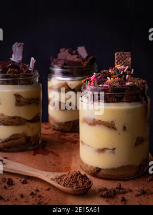 Tiramisu est un dessert italien aromatisé au café. Tiramisu dessert dans un pot avec garniture au chocolat et fond sombre Banque D'Images