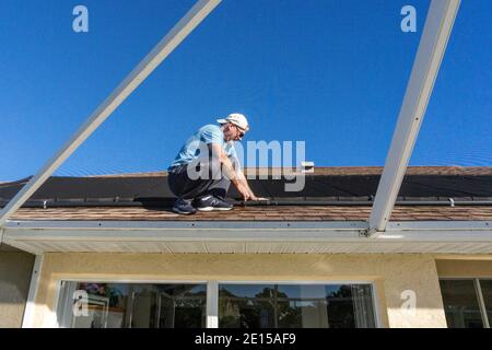 homme de 60 ans sur le toit inspectant le chauffage solaire Floride Banque D'Images