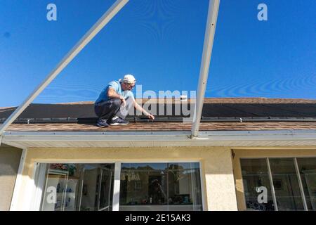 Vieil homme sur le toit inspectant le système de chauffage solaire de l'eau dans Floride Banque D'Images