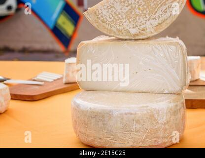 Tête de fromage entier et un peu de fromage coupé sur la table à vendre sur le marché un matin de vacances. Banque D'Images