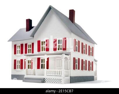 Maison de jouets blanche avec volets rouges et porche photographié un arrière-plan blanc Banque D'Images