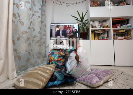 Chichester, West Sussex, Royaume-Uni. Florence, 5 ans, (à gauche) et sa sœur Isabelle, 8 ans, (à droite) regardant le Premier ministre britannique Boris Johnson prononcer son discours à 20h le lundi 4 janvier 2021, mettant le Royaume-Uni dans sa 3e école de fermeture. Crédit : Sam Stephenson/Alay Live News Banque D'Images