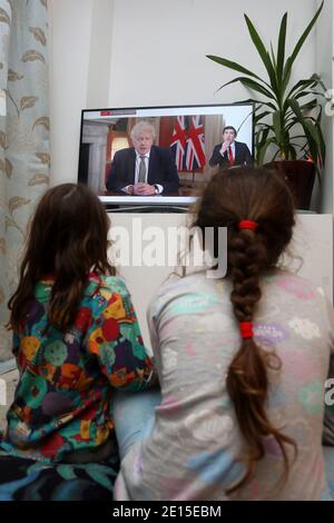 Chichester, West Sussex, Royaume-Uni. Florence, 5 ans, (à gauche) et sa sœur Isabelle, 8 ans, (à droite) regardant le Premier ministre britannique Boris Johnson prononcer son discours à 20h le lundi 4 janvier 2021, mettant le Royaume-Uni dans sa 3e école de fermeture. Crédit : Sam Stephenson/Alay Live News Banque D'Images