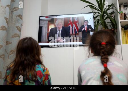 Chichester, West Sussex, Royaume-Uni. Florence, 5 ans, (à gauche) et sa sœur Isabelle, 8 ans, (à droite) regardant le Premier ministre britannique Boris Johnson prononcer son discours à 20h le lundi 4 janvier 2021, mettant le Royaume-Uni dans sa 3e école de fermeture. Crédit : Sam Stephenson/Alay Live News Banque D'Images