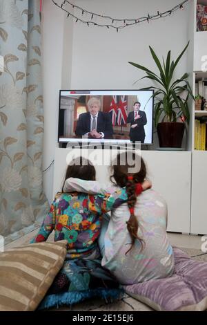 Chichester, West Sussex, Royaume-Uni. Florence, 5 ans, (à gauche) et sa sœur Isabelle, 8 ans, (à droite) regardant le Premier ministre britannique Boris Johnson prononcer son discours à 20h le lundi 4 janvier 2021, mettant le Royaume-Uni dans sa 3e école de fermeture. Crédit : Sam Stephenson/Alay Live News Banque D'Images