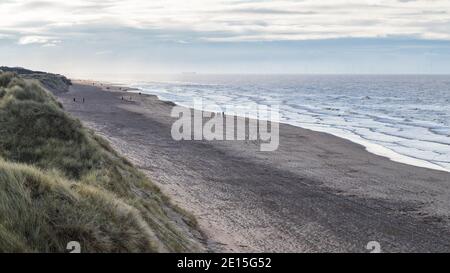 Les marcheurs sur la plage de Formby créent des empreintes de pieds dans le sable, vu en janvier 2021 depuis une grande dune de sable. Banque D'Images