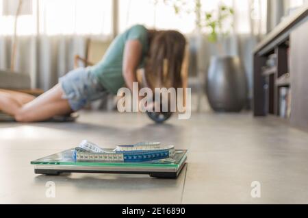 Concept de l'échec dans la perte de poids, des échelles au premier plan et frustré femme dans le fond. Banque D'Images