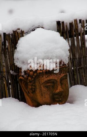 Vieille tête de bouddha de terre cuite recouverte de neige Banque D'Images