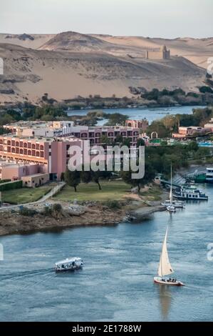 Cette scène tranquille avec des voiliers de Felucca sur le Nil se trouve dans l'ancienne ville égyptienne d'Assouan, connue auparavant sous le nom de ville nubienne, en regardant vers le sud vers le site de sépulture des tombes des Nobles et le Mausolée de l'Aga Khan. La région est importante car elle était un poste de transit pour l'armée britannique qui passait par l'Égypte au Soudan d'où Lord Kitchener a rétabli la paix dans la région. Pour cela, il a été doué de la terre connue sous le nom de Kitcheners Island que Lord Kitchener a transformée en l'un des premiers jardins botaniques au monde Banque D'Images