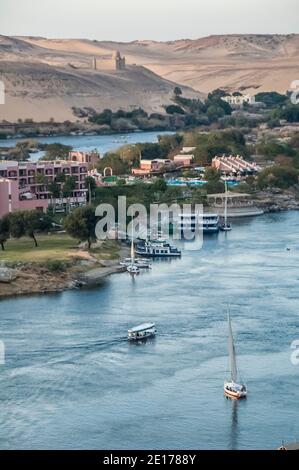 Cette scène tranquille avec des voiliers de Felucca sur le Nil se trouve dans l'ancienne ville égyptienne d'Assouan, connue auparavant sous le nom de ville nubienne, en regardant vers le sud vers le site de sépulture des tombes des Nobles et le Mausolée de l'Aga Khan. La région est importante car elle était un poste de transit pour l'armée britannique qui passait par l'Égypte au Soudan d'où Lord Kitchener a rétabli la paix dans la région. Pour cela, il a été doué de la terre connue sous le nom de Kitcheners Island que Lord Kitchener a transformée en l'un des premiers jardins botaniques au monde Banque D'Images