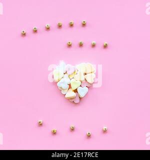 Concept de vacances créatives de l'amour. Coeur fait de bonbons colorés sur fond rose. Texte Suivez votre coeur fait de perles de bois. Saint-Valentin Banque D'Images