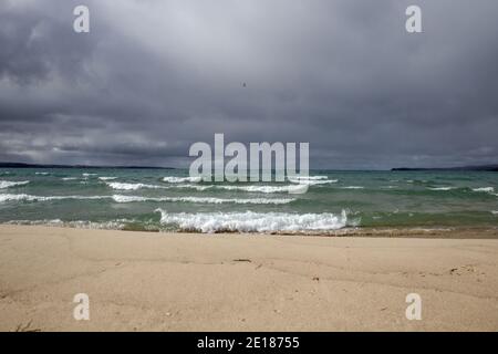 Tempête sur l'horizon. Les vagues s'écrassent sur une plage du lac Michigan dans le parc national de Petoskey avec des nuages de tempête menaçants sombres à l'horizon. Banque D'Images