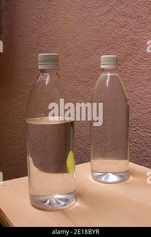 Étude de deux bouteilles en verre remplies d'eau tableau sur fond marron granuleux Banque D'Images