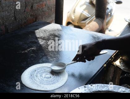 Un Tamoul cuire la préparation d'un Dosa. Banque D'Images