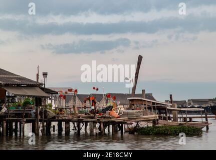 Bangkok, Thaïlande - 04 janv. 2021 : petit ferry stationné devant l'ancienne maison en bois au bord de la rivière Chao Phraya. Mise au point sélective. Banque D'Images