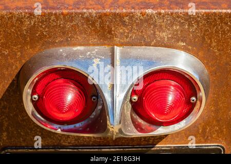 Gros plan d'un feu arrière de voiture Chevrolet 1958 rouillé avec deux lentilles rouges et garniture chromée sous la lumière du soleil Banque D'Images
