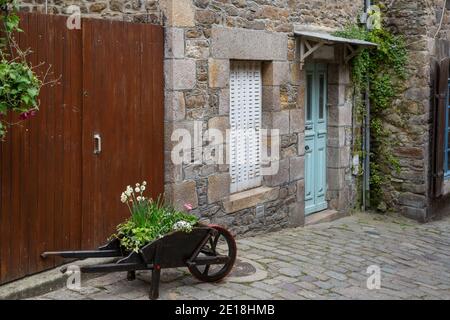 Jonquilles et autres fleurs printanières dans une brouette à l'extérieur d'un chalet en Bretagne, en France Banque D'Images