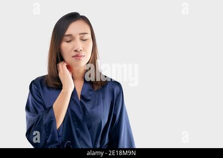 Les femmes asiatiques dans la robe bleu foncé se grattent le cou en raison de démangeaisons sur un fond gris. La femelle a un bras d'attelage. Le concept d'allerg Banque D'Images