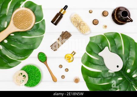 Brosse pour le corps, épurateur, pierre ponce, sel de mer, huiles essentielles naturelles avec feuilles vertes sur bois blanc. Produits de traitement de la cellulite et du spa Banque D'Images