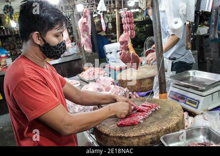 Manille, Philippines. 5 janvier 2021. Un vendeur portant un masque fabrique des saucisses sur un marché de Manille, aux Philippines, le 5 janvier 2021. L'inflation annuelle aux Philippines s'est accélérée pour atteindre 3.5 pour cent en décembre 2020, contre 3.3 pour cent en novembre 2020, tirée par les augmentations des aliments et des boissons non alcoolisées, a déclaré mardi l'Autorité statistique philippine (PSA). Dennis Mapa, chef de PSA, a déclaré à une conférence de presse virtuelle que c'était l'inflation la plus élevée enregistrée depuis mars 2019. Crédit: Rouelle Umali/Xinhua/Alamy Live News Banque D'Images