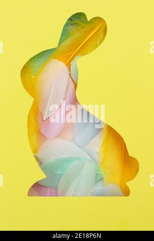 Carte de vœux de Pâques dans des couleurs tendance. Le jaune et le gris sont les couleurs de 2021. Une silhouette de lapin est coupée en papier. Arrière-plan de multi Banque D'Images