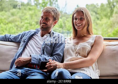 Smiling couple sitting on sofa Banque D'Images