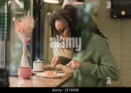 femme afro-américaine en lunettes tenant des couverts près de la tarte plaque Banque D'Images