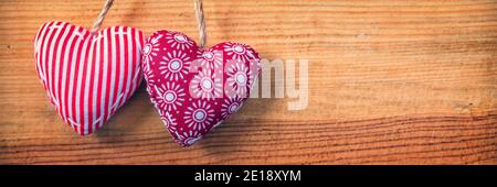 Deux coeurs en tissu rouge sur fond de bois, panoramique vieux valentines day bannière web Banque D'Images