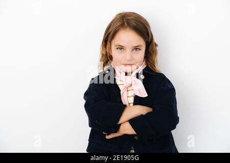 Portrait d'une petite fille brunette, elle se tient contre un mur blanc Banque D'Images