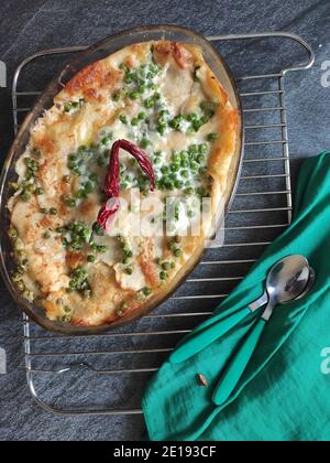 Lasagnes aux pois verts faits maison dans un fond sombre et un nappe verte Banque D'Images