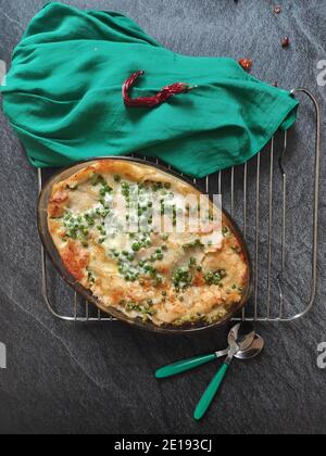 Lasagnes aux pois verts faits maison dans un fond sombre et un nappe verte Banque D'Images