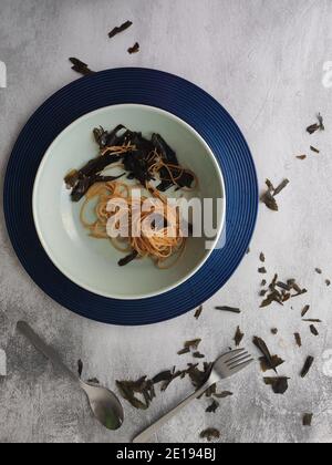 Spaghetti d'algues kombu dans une assiette bleue Banque D'Images