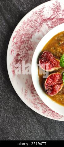 Figues violettes dans une soupe d'orange dans un ancien anglais bol de style Banque D'Images