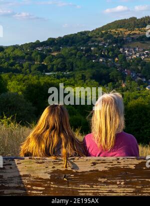 Deux personnes sur un banc en bois admirant la vue près de Wirksworth et Cromford dans le Derbyshire Dales partie du Peak District England UK en été. Banque D'Images