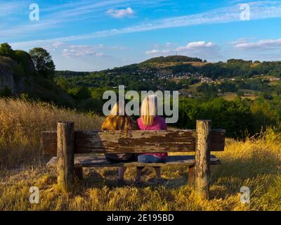 Deux personnes sur un banc en bois admirant la vue près de Wirksworth et Cromford dans le Derbyshire Dales partie du Peak District England UK en été. Banque D'Images