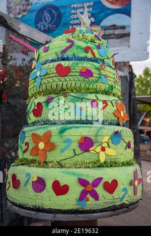 Un arbre de Noël fait de pneus de voiture qui ont été peints en vert et décorés avec des cannes de bonbons, des coeurs et des fleurs coupées à partir de papiers colorés. Banque D'Images