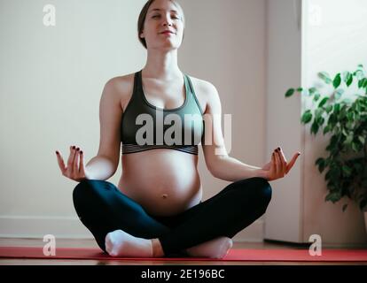 Jeune femme enceinte exercice yoga à la maison Banque D'Images